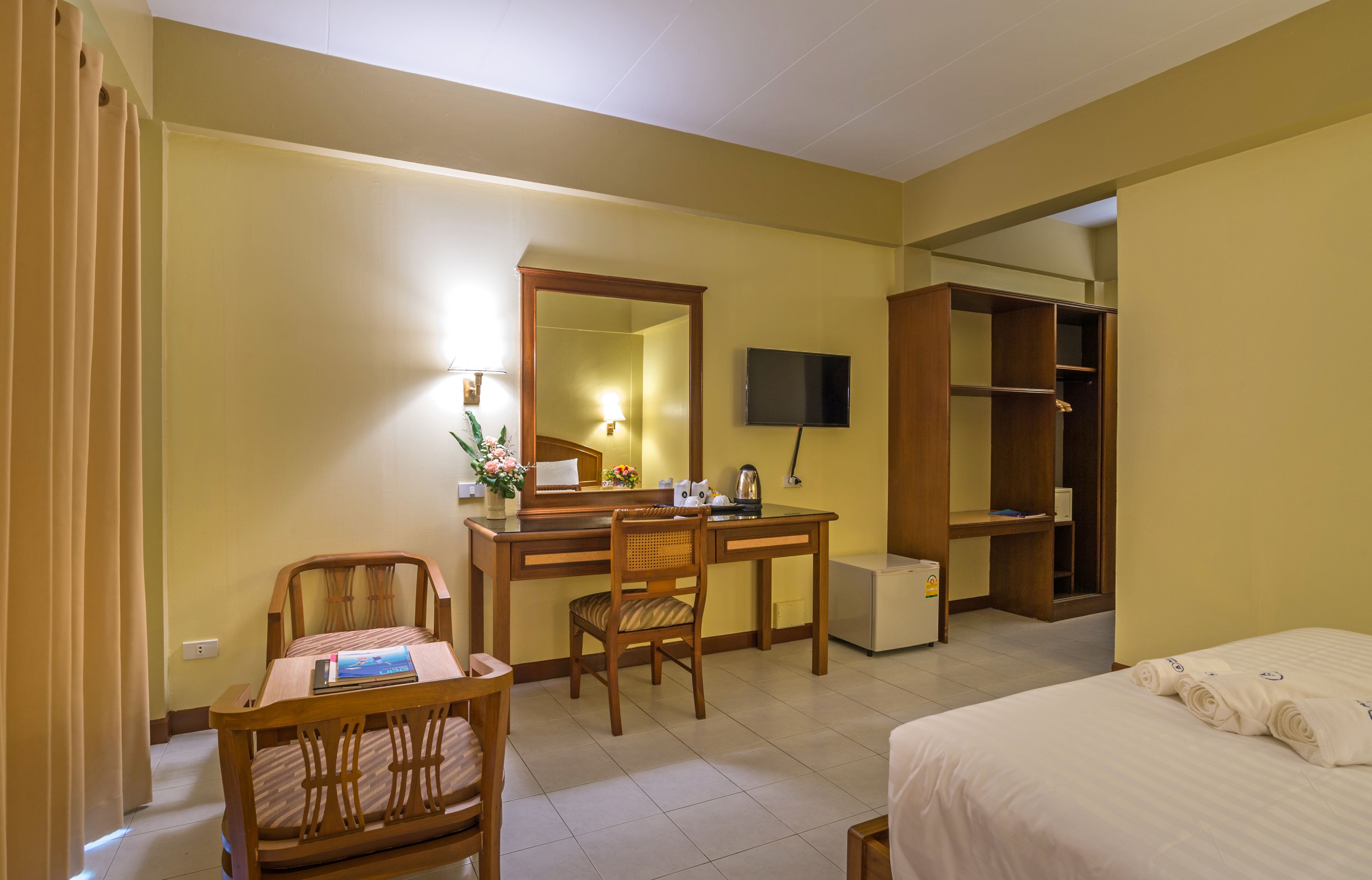 Una habitación de hotel con cama, escritorio, silla, televisor y armario.