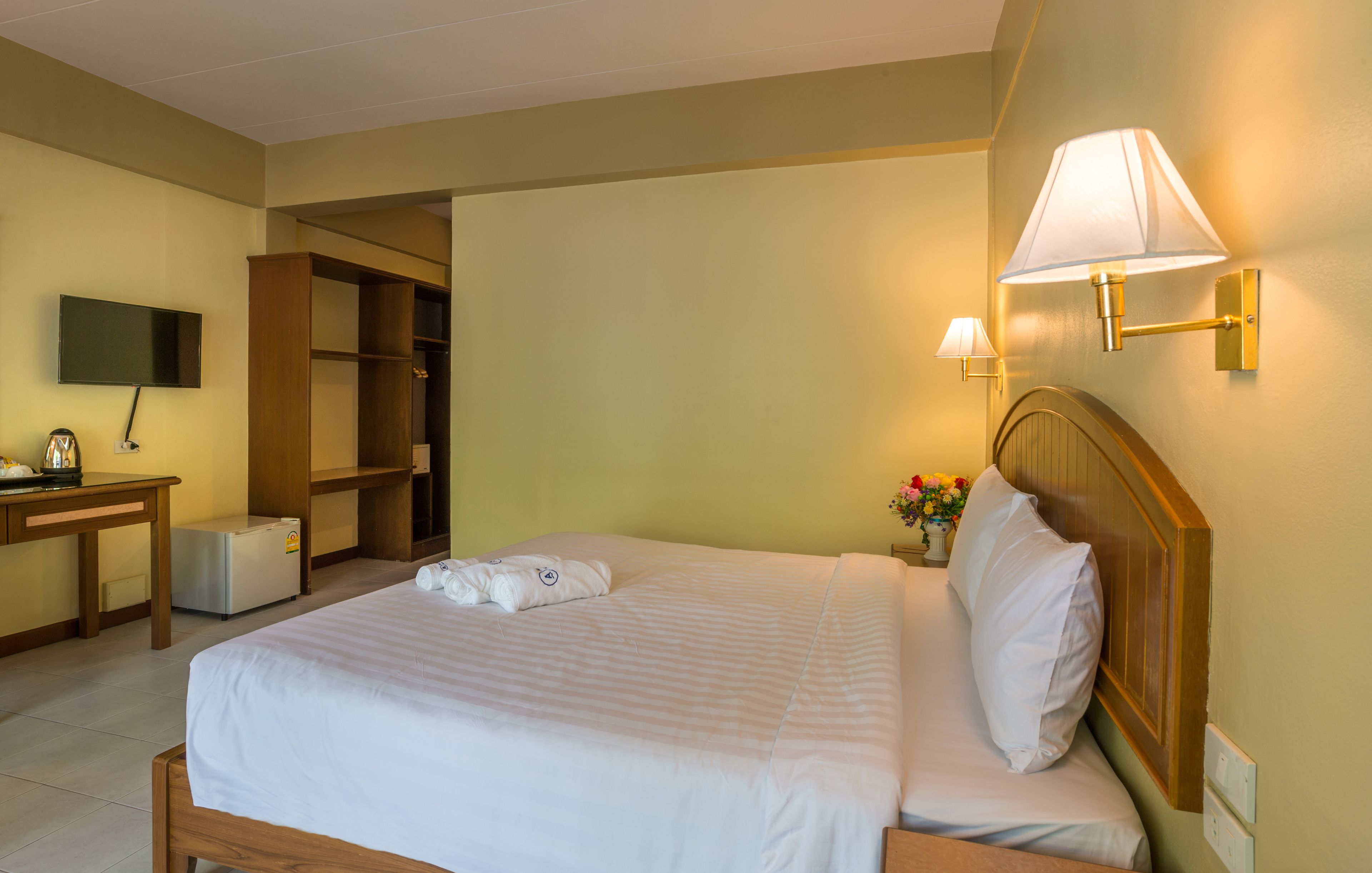 Une chambre d’hôtel comprenant un lit, une table de chevet, une télévision, une armoire et une lampe.