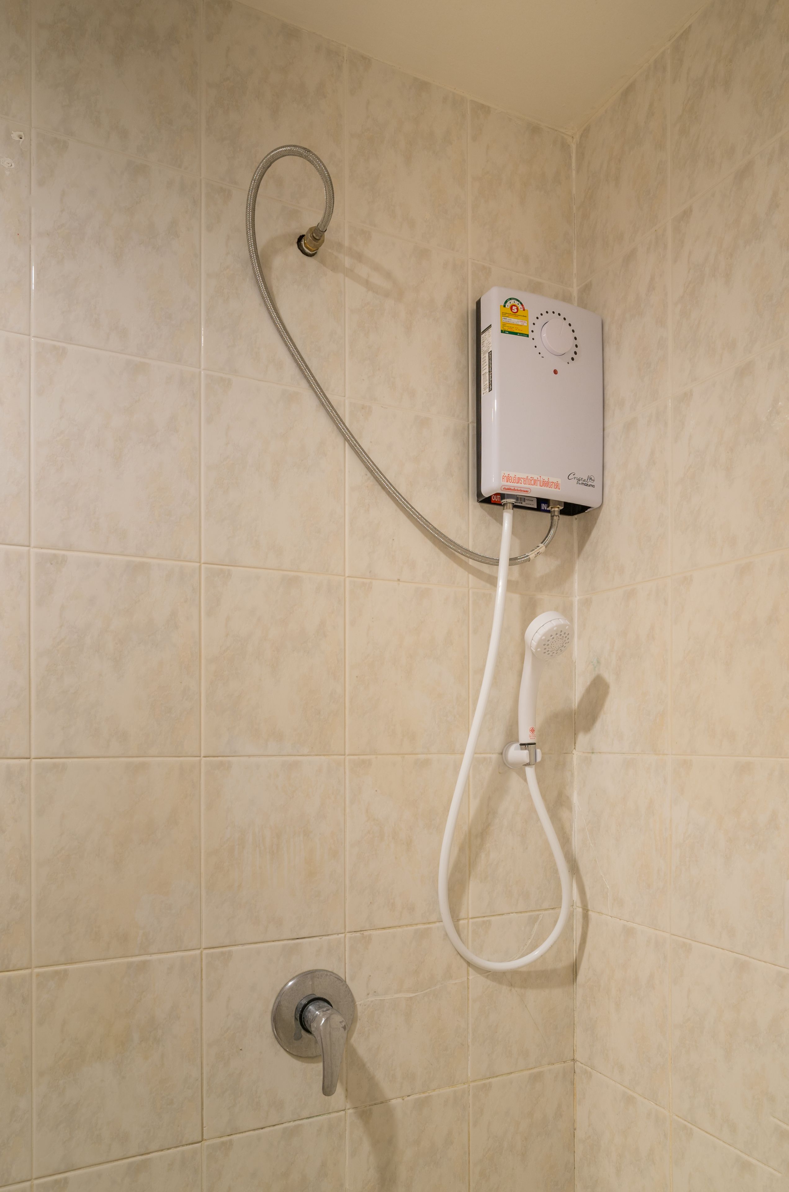 A shower with a handheld showerhead and a wall-mounted control unit.