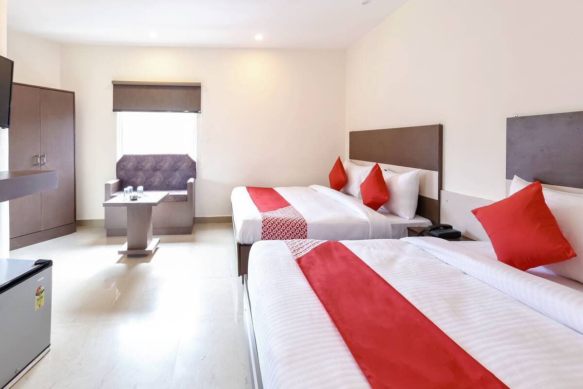 Une chambre d’hôtel avec deux lits, un bureau, un canapé et un mini-bar.