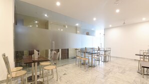 Un vaste espace dédié à la salle à manger, doté d’un sol en marbre et de mobilier moderne, notamment des tables et des chaises.