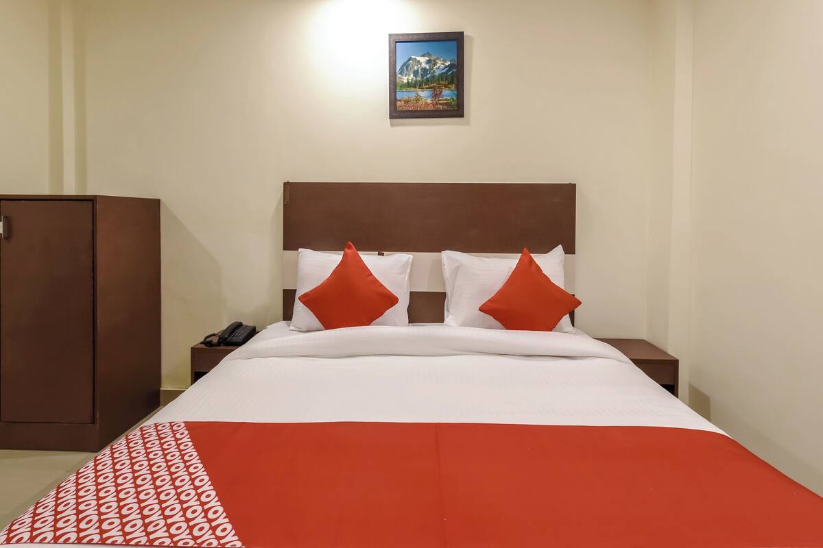 Une chambre d’hôtel comprenant un lit, une table de chevet, un téléphone et une armoire.