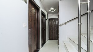 Ein Korridor mit Holztüren, einer Treppe mit Metallgeländern und einer Deckenleuchte.