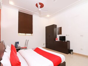 A hotel room with a bed, a desk, a television, and a wardrobe. - OYO 18851 Smart Signature (Gurugram)