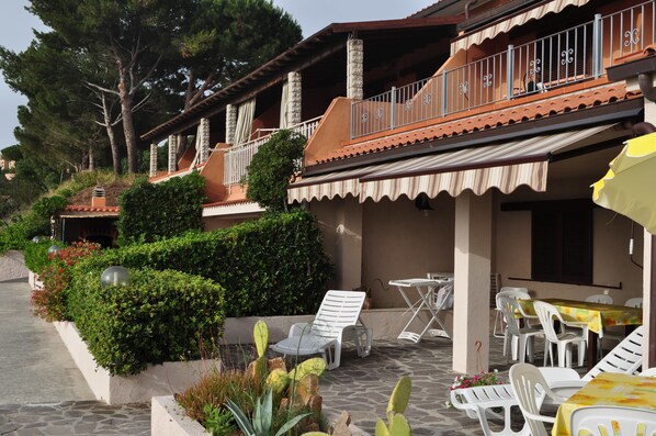Un hotel con asientos al aire libre, un patio cubierto y un camino de piedra.