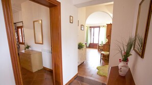 A hallway with a wooden floor, a radiator, a wooden cabinet, a mirror, and a vase with plants. - Appartamenti Il Sogno (Capoliveri)