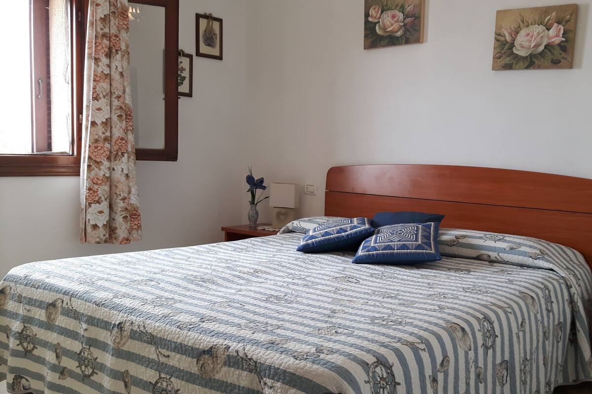 Une chambre à coucher avec une tête de lit en bois, une couvre-lit à rayures et deux coussins assortis.