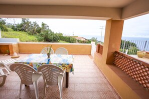 Un patio con una mesa y sillas, vistas al mar y suelo de baldosas.