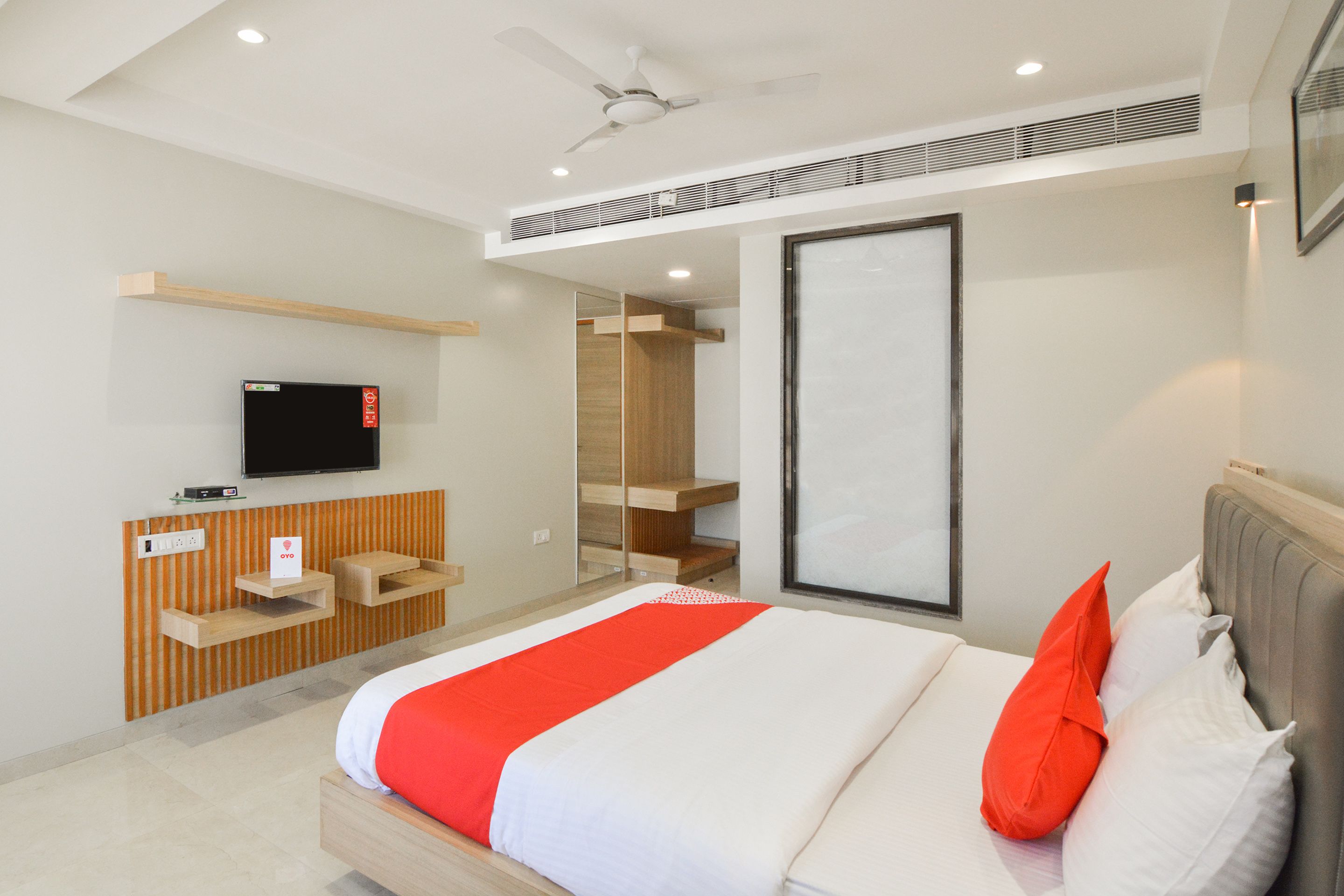 Una habitación de hotel moderna con cama, televisión, armario y ventilador de techo.