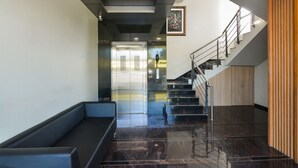 Un intérieur moderne avec un escalier, un banc et un tableau encadré au mur.