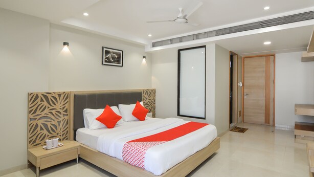 Une chambre d’hôtel moderne équipée d’un grand lit, d’une table de chevet, d’une armoire et d’un ventilateur de plafond.