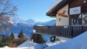 A mountain lodge with a wooden exterior, a balcony with a view of snow-covered mountains, and a sign indicating a restaurant. - Premium Chalet a. d.Piste in ski u. Hiking area BELALP with panoramic views (Blatten)