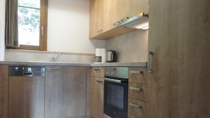 A kitchen with wooden cabinets, a dishwasher, an oven, and a coffee maker. - Premium Chalet a. d.Piste in ski u. Hiking area BELALP with panoramic views (Blatten)