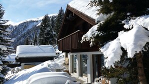 A wooden chalet with a balcony, surrounded by snow-covered trees and mountains. - Premium Chalet a. d.Piste in ski u. Hiking area BELALP with panoramic views (Blatten)