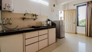 A modern kitchen with a built-in oven, a refrigerator, and a water dispenser. - OYO 22730 Home Pool View 1BHK Vagator Beach (Vagator)