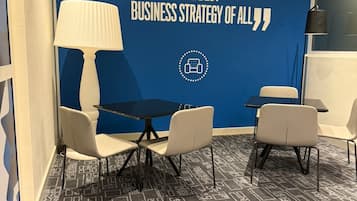 A room with a blue wall featuring a quote about customer satisfaction, a table with chairs, a lamp, and a patterned carpet.