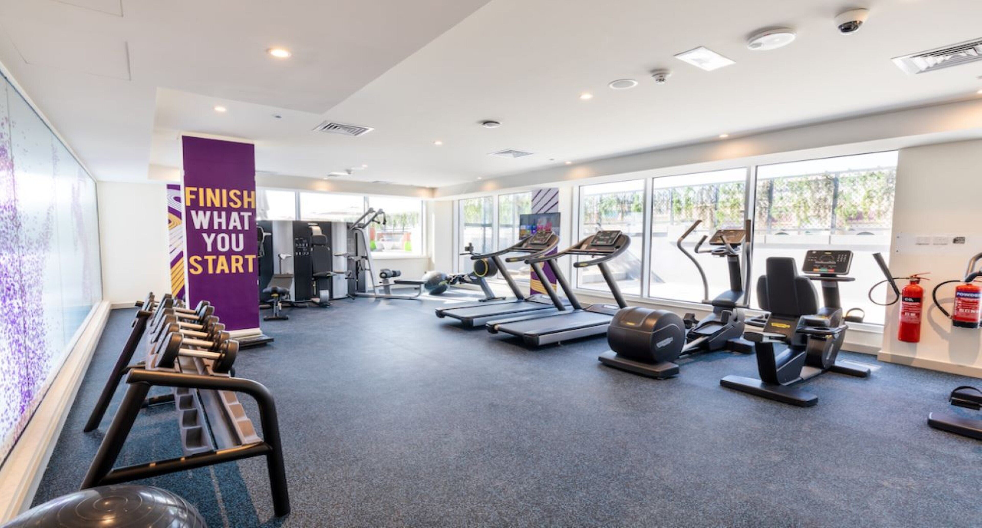 Un gimnasio moderno con cintas de correr, elípticas y equipo de pesas.