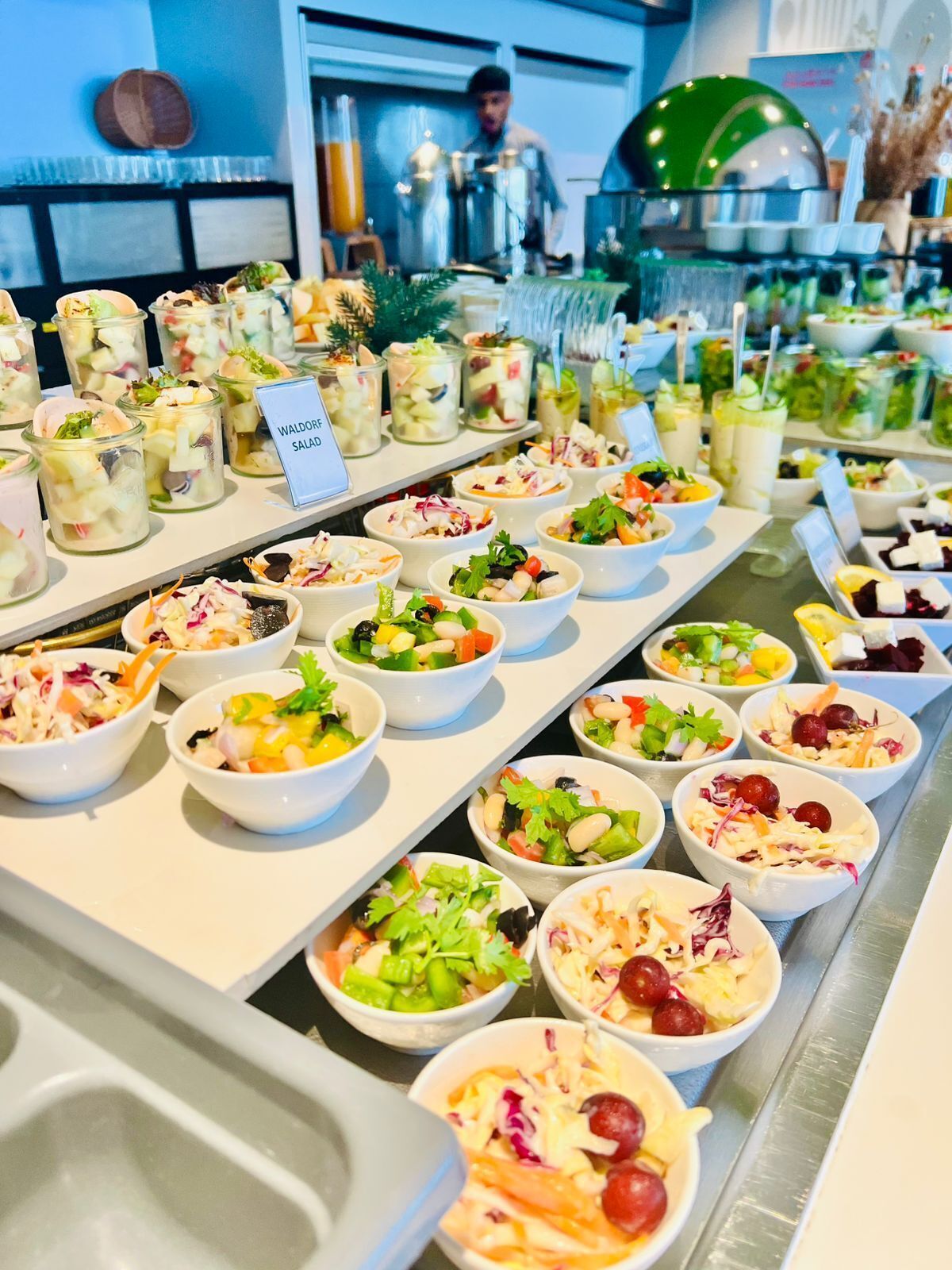 A buffet with various salads and dishes, including Waldorf Salad and other mixed salads.