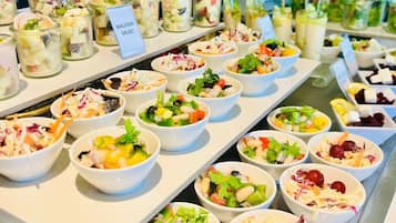 A buffet with various salads and dishes, including Waldorf Salad and other mixed salads.
