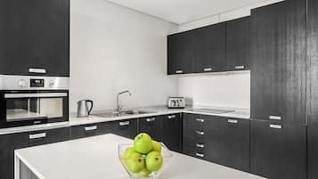 A modern kitchen with dark cabinetry, a white countertop, a built-in oven, a sink, and a toaster.