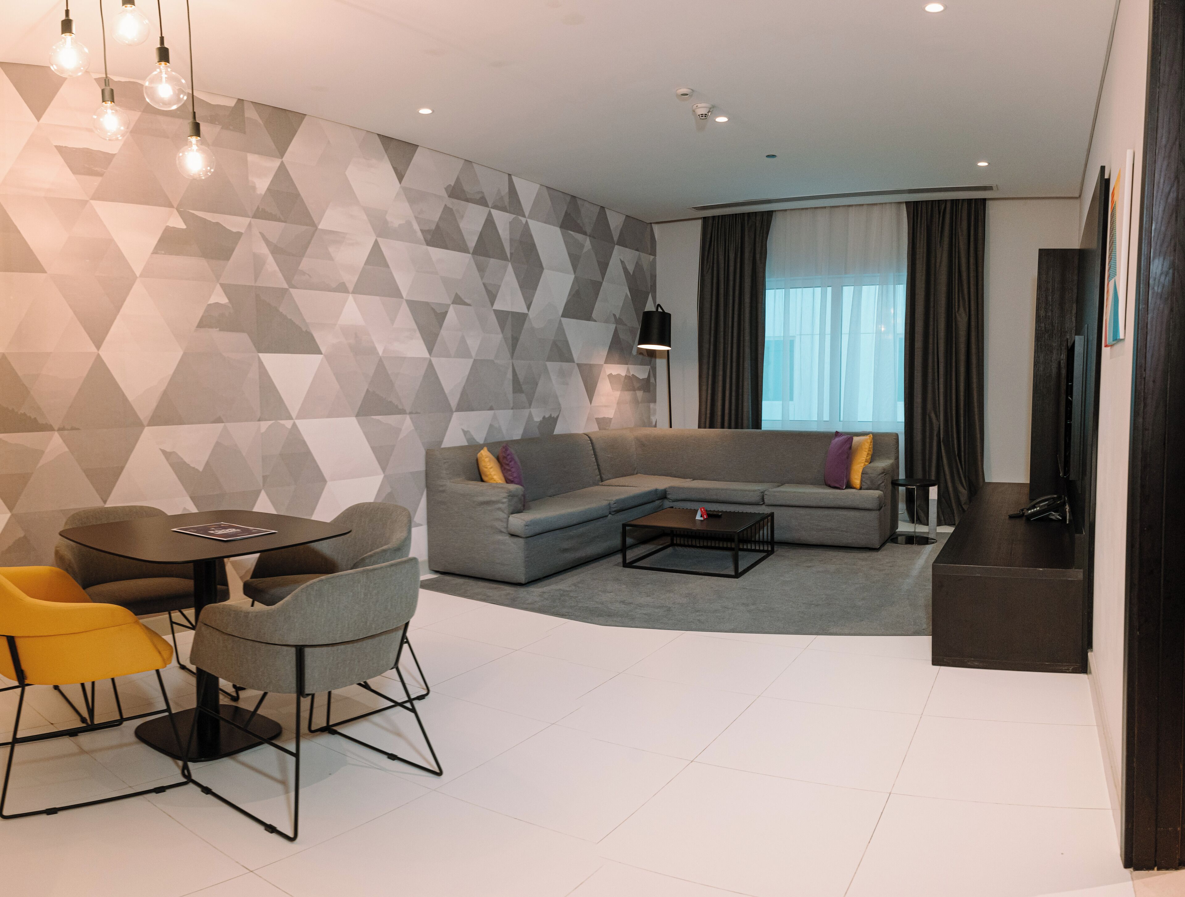 A modern living room with a sectional sofa, a round coffee table, and a dining area with chairs.