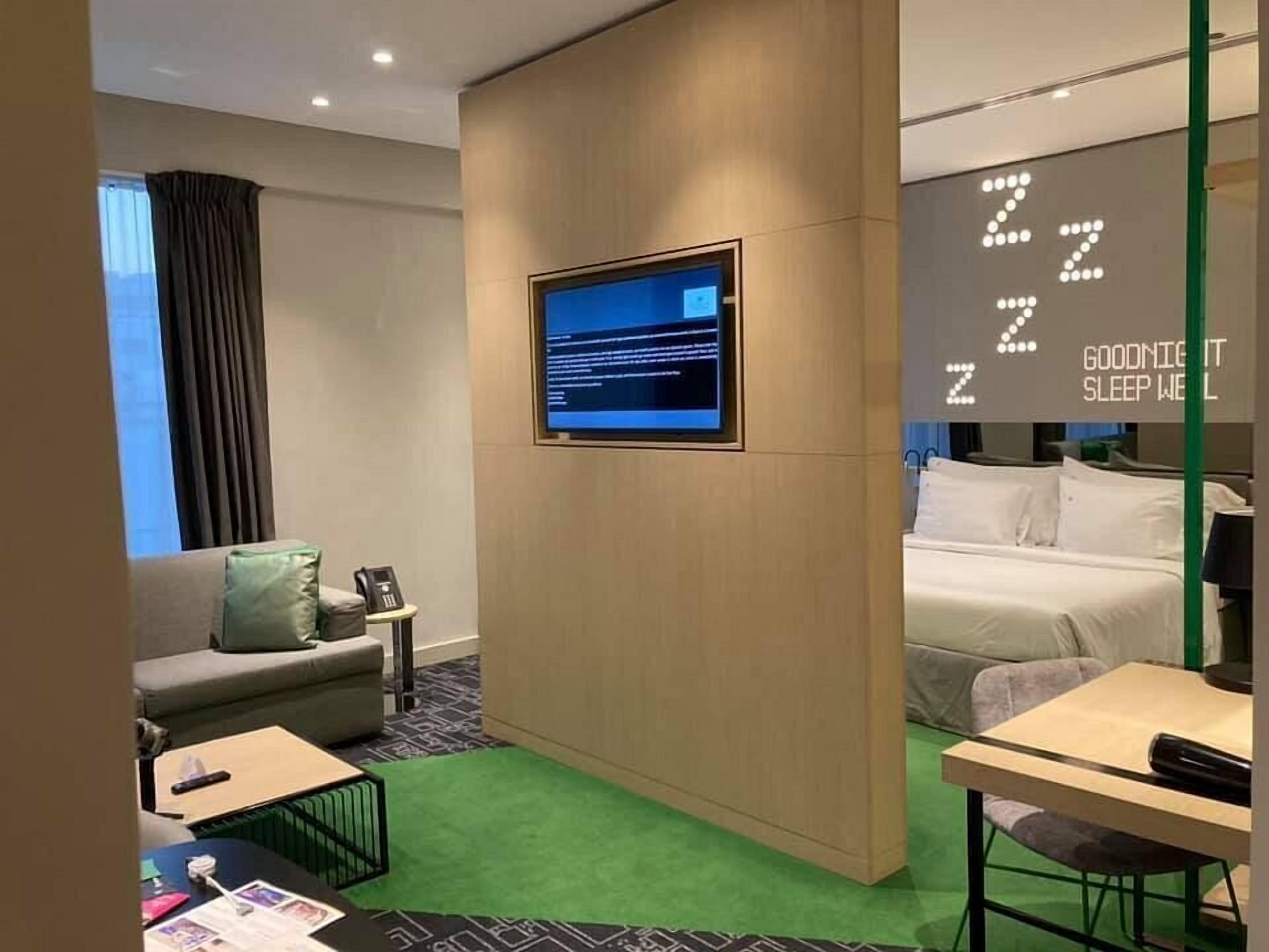 A hotel room with a bed, a desk, a sofa, and a television.