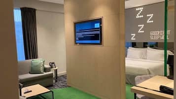 Ein Hotelzimmer mit Bett, Schreibtisch, Sofa und Fernseher.