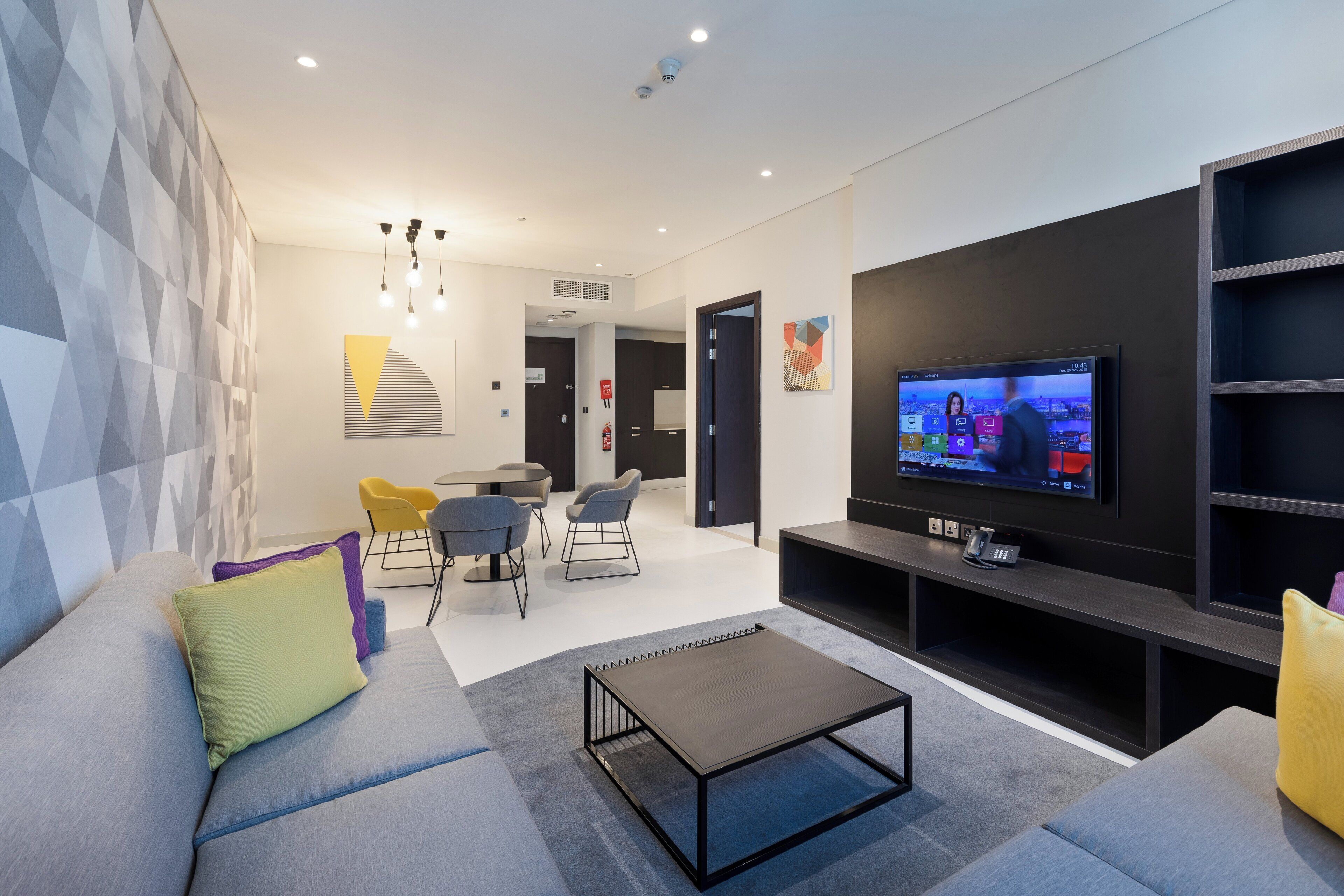 Un saló modern amb televisió plana, un sofà, una taula de centre i una zona de menjador amb cadires.