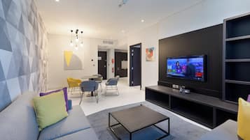 Un saló modern amb televisió plana, un sofà, una taula de centre i una zona de menjador amb cadires.