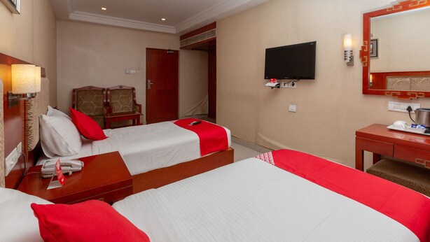 Una habitación de hotel con dos camas, un escritorio, una silla, un televisor y un espejo.