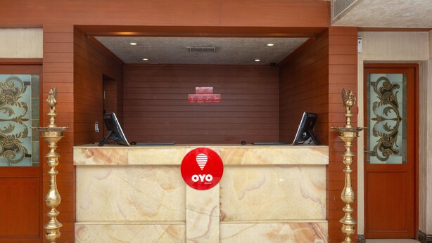 Un mostrador de recepción con encimera de mármol, dos elegantes soportes de bronce y un letrero rojo de OYO Rooms.