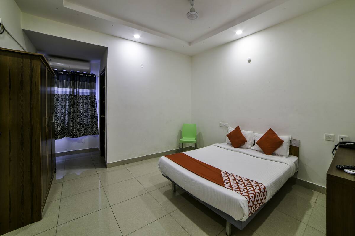 Een hotelkamer met een bed, bureau, stoel en garderobe.