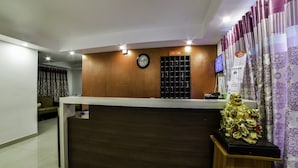 A reception desk with a clock, a bulletin board, and a statue. - OYO 14184 Hotel Green Stone (Hyderabad)