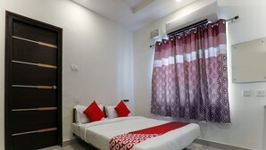 A bedroom with a bed, a dark wooden door, a patterned curtain, and a white wall with an air conditioning unit. - OYO 14184 Hotel Green Stone (Hyderabad)
