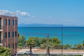 A coastal building with a view of the sea and mountains in the distance.