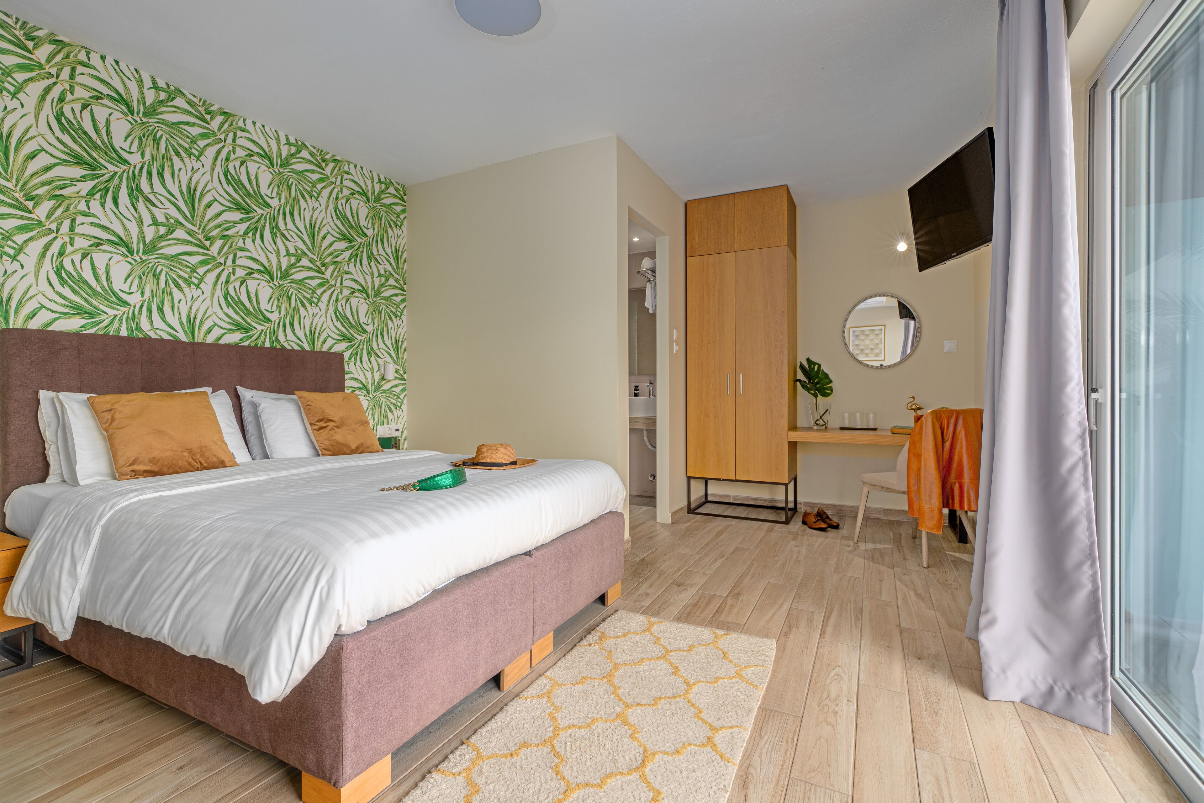 A bedroom with a bed, a wardrobe, a desk, and a mirror.