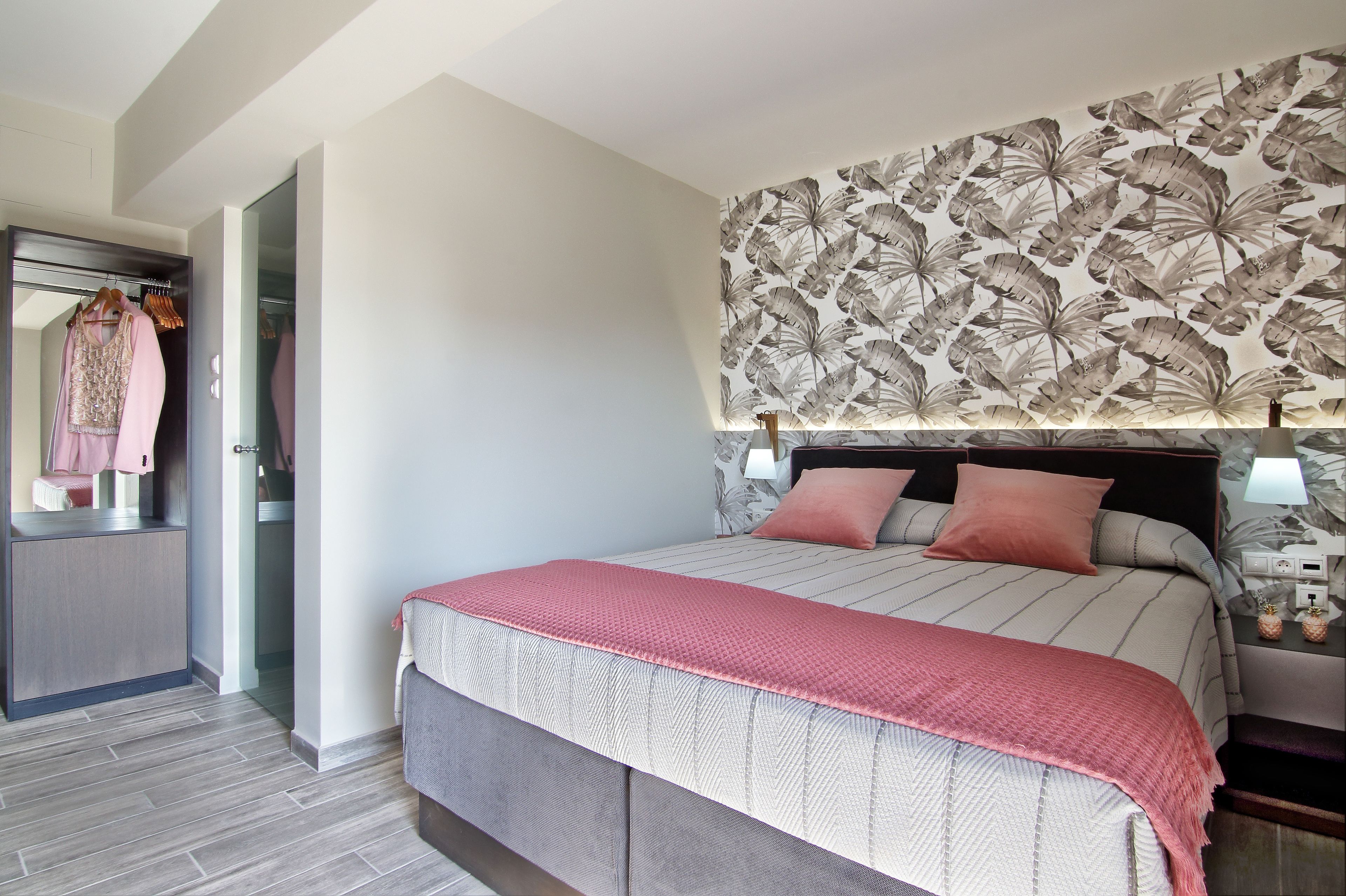 Un dormitorio con cama, armario, espejo y pared con diseño de hojas.