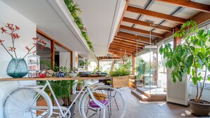A modern kitchen with a wooden countertop, a white bicycle, and various plants. - Maison 66 Riviera Hotels (Alimos)