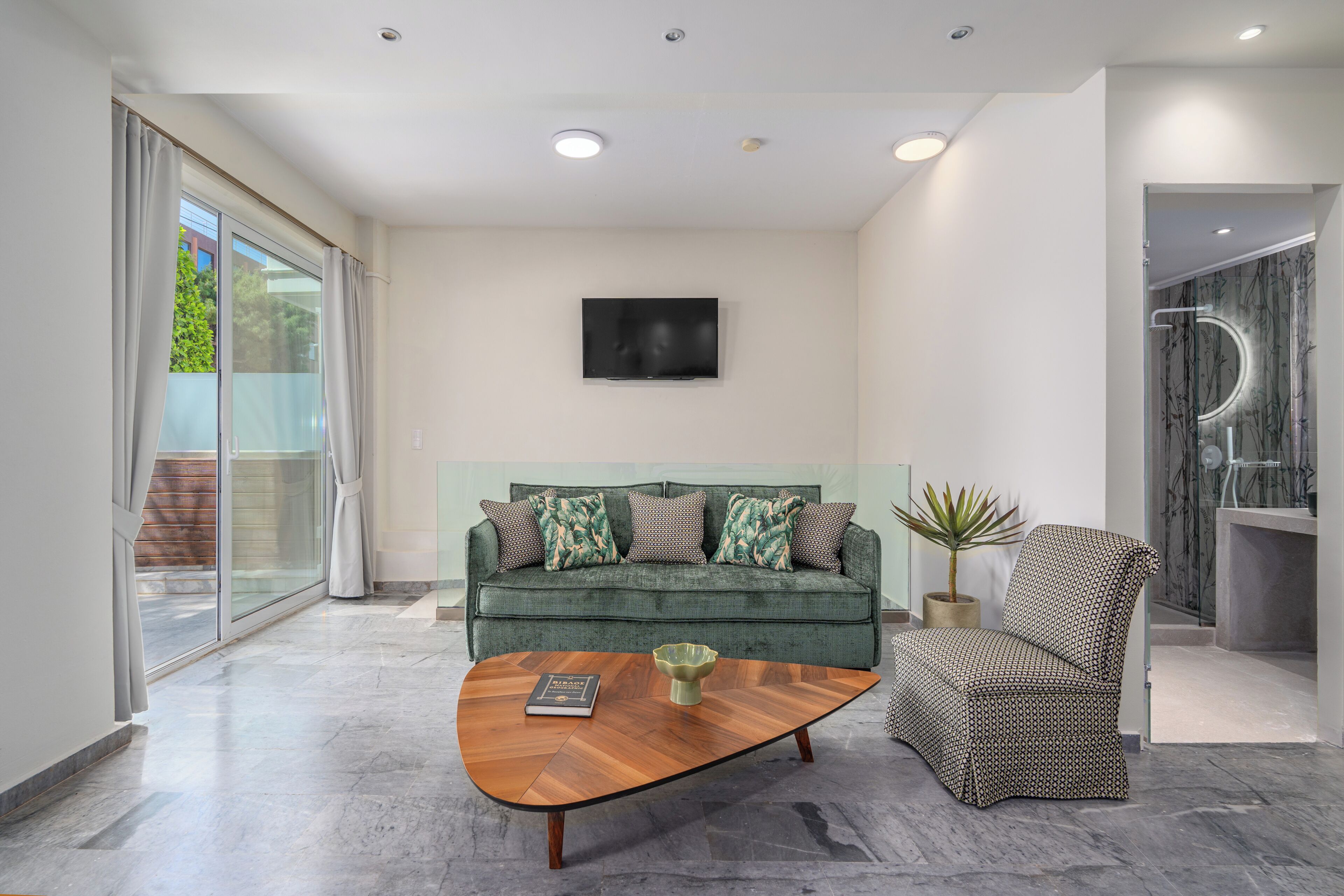A modern living room with a sofa, armchair, coffee table, and a flat-screen TV.