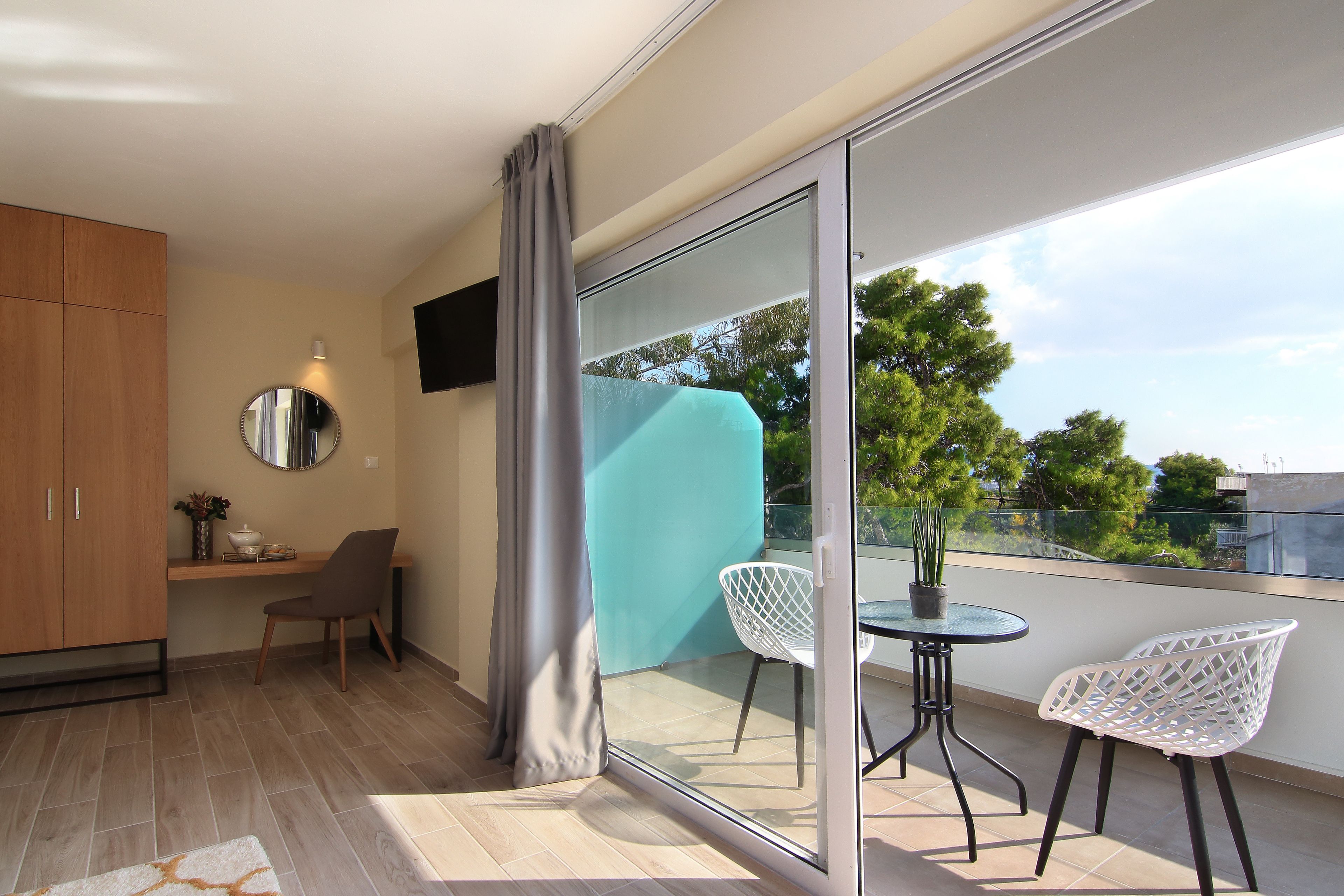 A modern balcony with a glass door, a small table, two chairs, and a potted plant.