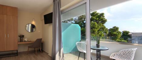 A modern balcony with a glass door, a small table, two chairs, and a potted plant.