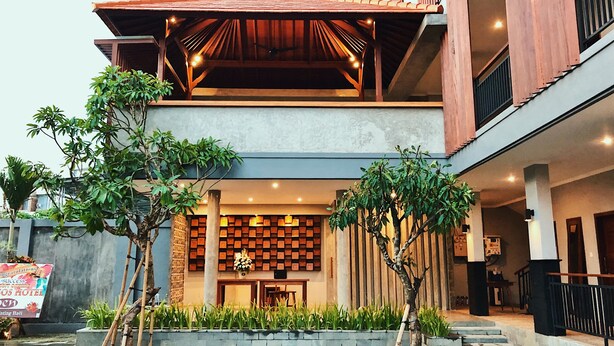 A modern hotel with a covered outdoor area, a reception desk, and a wall of framed certificates. - Perissos Echo Beach (Canggu)