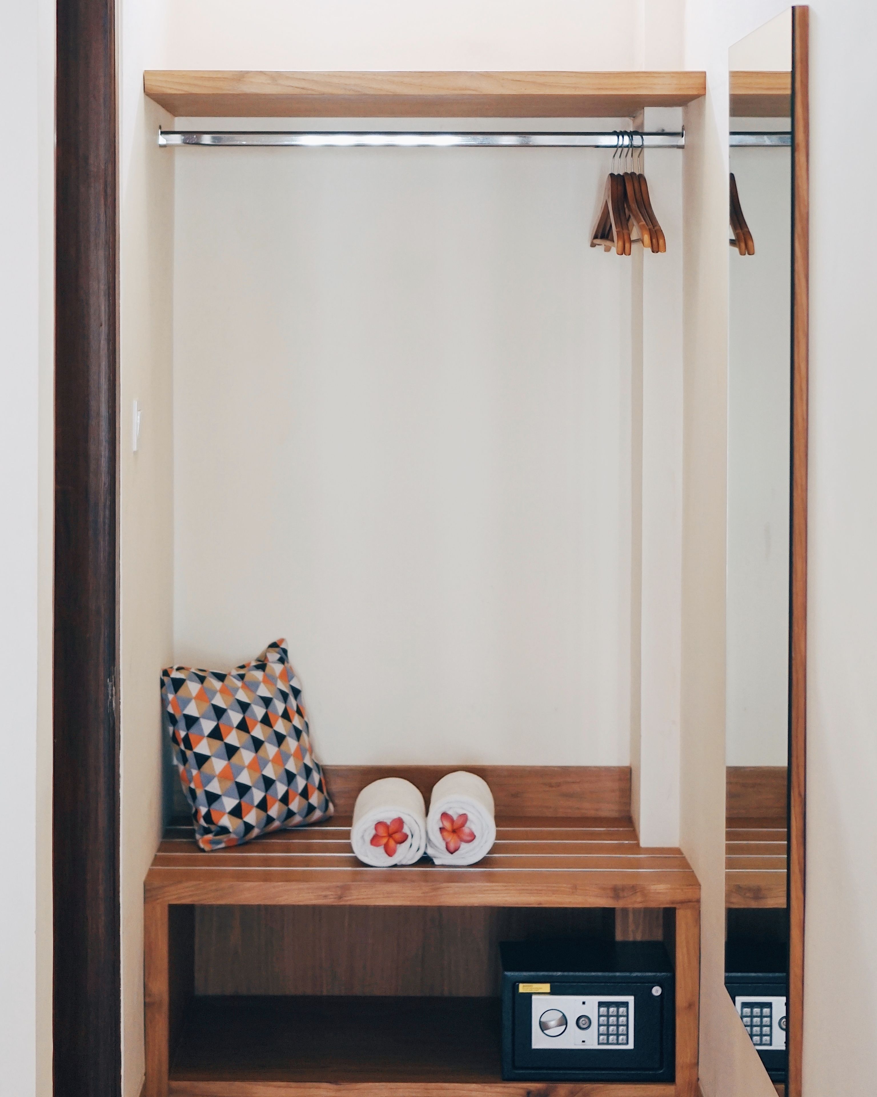 A small wooden bench with a pillow and two towels with floral designs.