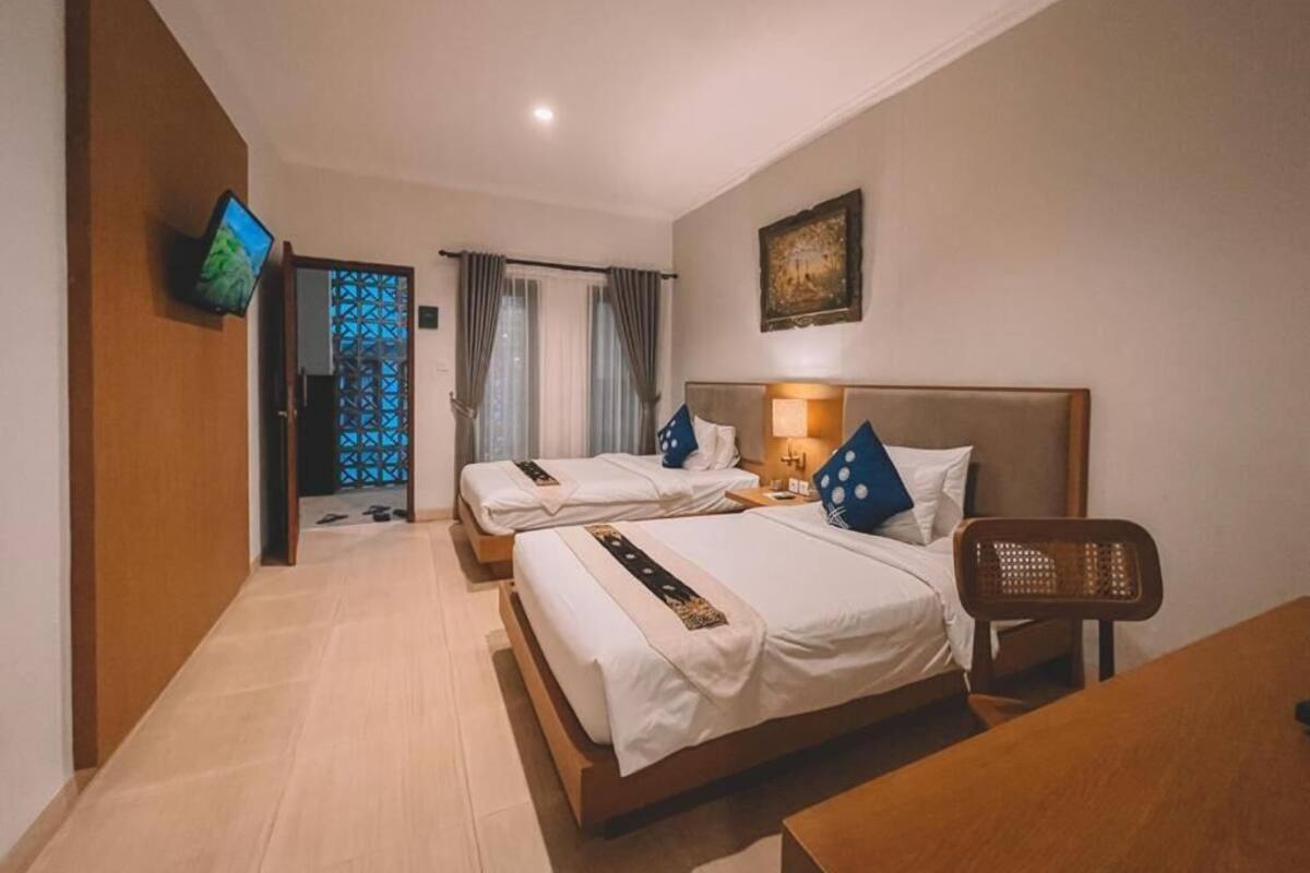 A hotel room with two beds, a TV, a desk, and a chair.
