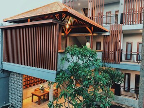 A multi-story building with a wooden balcony, a covered outdoor seating area, and a staircase. - Perissos Echo Beach (Canggu)