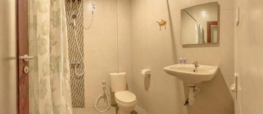A bathroom with a shower, toilet, sink, and mirror.