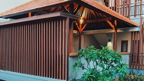 A modern building with a sloped roof, wooden beams, and a small outdoor seating area with a table and chairs. - Perissos Echo Beach (Canggu)
