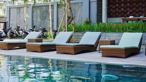 A poolside area with lounge chairs and a concrete wall. - Perissos Echo Beach (Canggu)