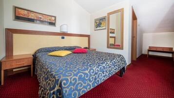 Une chambre d’hôtel avec un grand lit, une table de chevet, une commode, un banc et un miroir au mur.