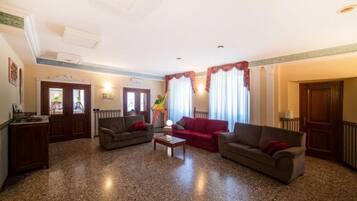 A spacious living room with a granite floor, two sofas, a coffee table, and a large window with curtains.